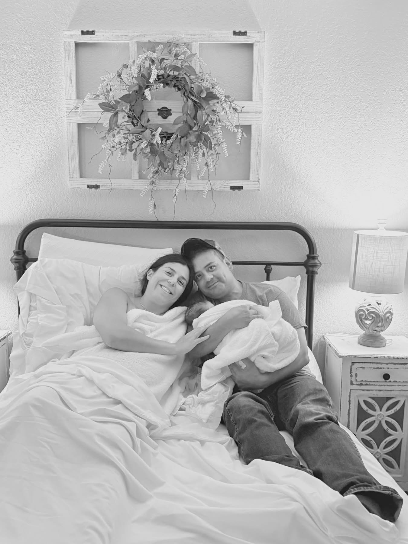 A mother and father resting in bed with their newborn, moments after birth